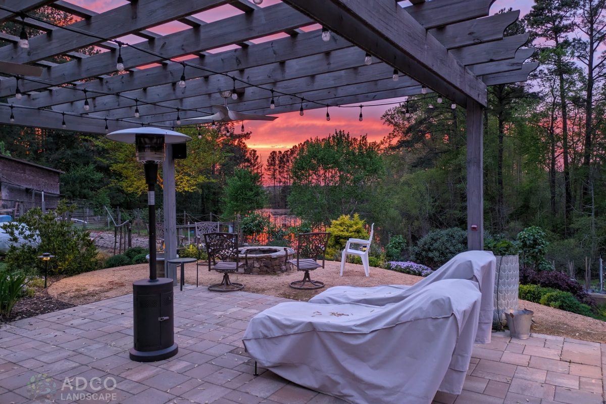 a patio with a pergola and a fire pit.